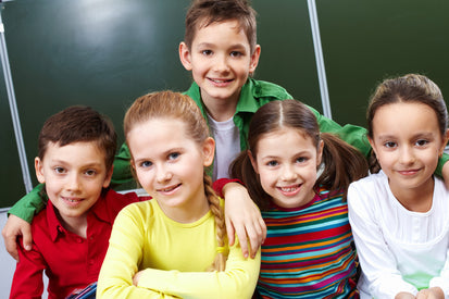 Five children posing together in front of a chalkboard